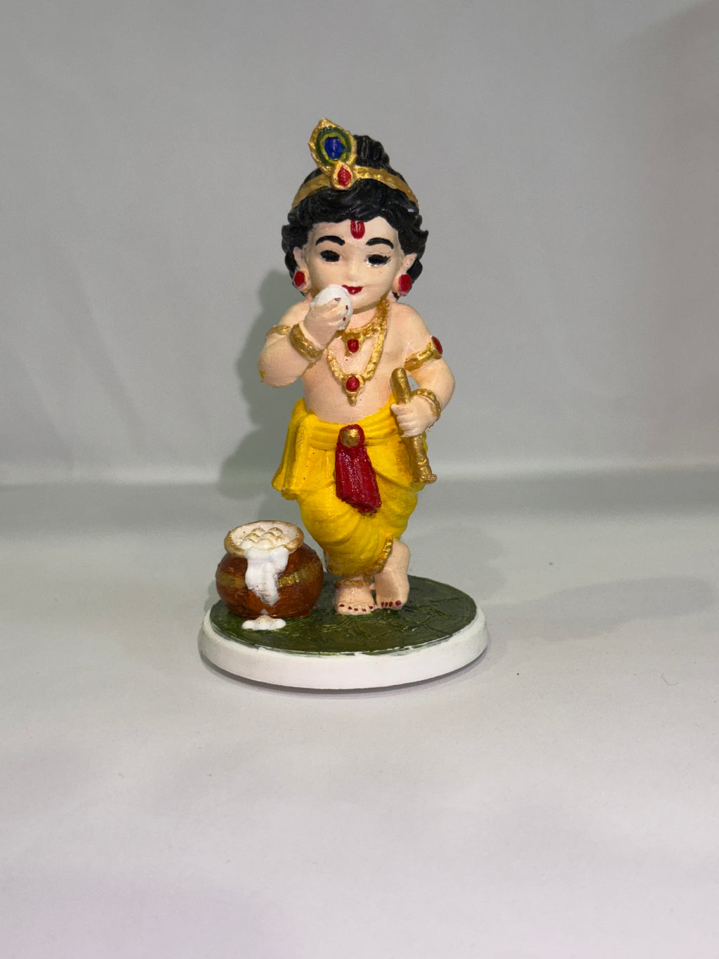 Captures the classic, beloved "Makhan Chor" pose—complete with the traditional pot of butter (matki), flute, and peacock feather crown.