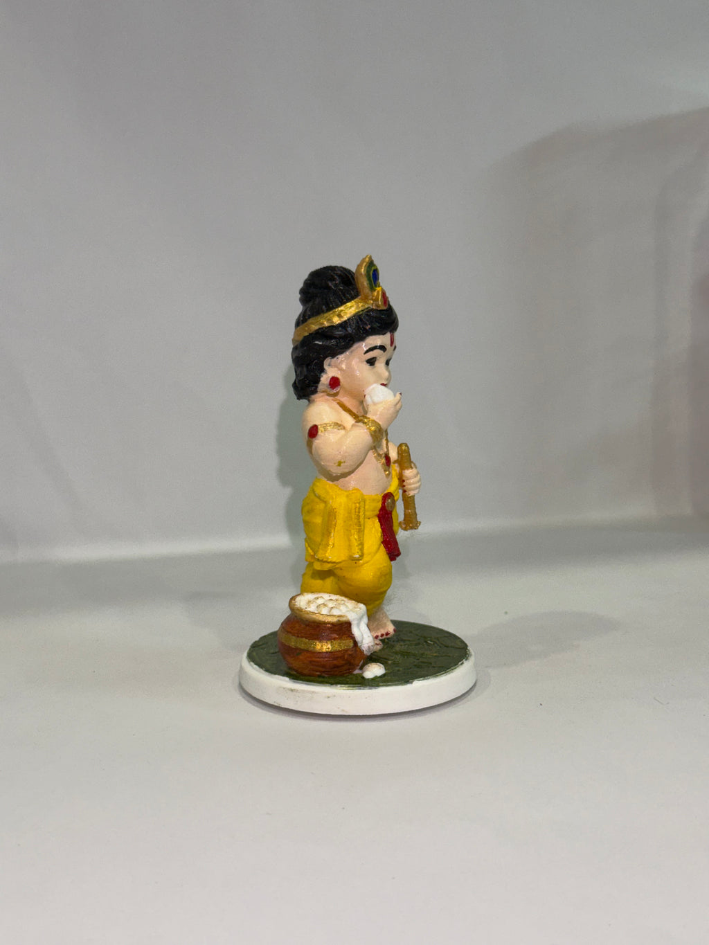 Captures the classic, beloved "Makhan Chor" pose—complete with the traditional pot of butter (matki), flute, and peacock feather crown.
